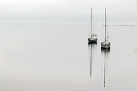 Batiscan: Two small boats sit isolated on a calm, grey horizon in Batiscan, Quebec