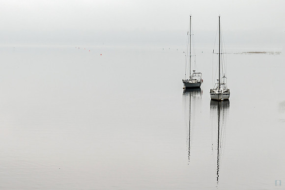 Batiscan: Two small boats sit isolated on a calm, grey horizon in Batiscan, Quebec
