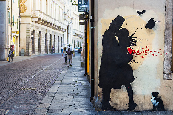 Padua: A lone figure walks past a street art mural in an ancient street in Padua