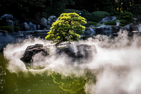 Fukuoka Hakata: A mist-shrouded Japanese garden in Fukuoka Hakata featuring lush greenery and calm water