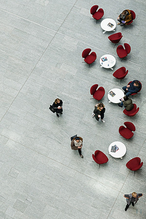 Vilnius K29K29  Minimalist aerial photography featuring a serpentine arrangement of red chairs on grey tiles with scattered figures