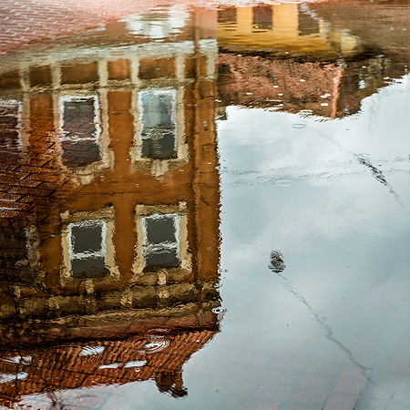 Vilnius: A vibrant reflection of historic Vilnius architecture in a rain-slicked cobblestone street