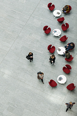 Vilnius K29K29  Minimalist aerial photography featuring a serpentine arrangement of red chairs on grey tiles with scattered figures
