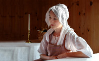 Historically-themed portrait of Megan Louisbourg in 18th-century attire within a period interior