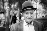 Grayscale portrait of an elderly man in Tehran wearing a bowler hat and jacket