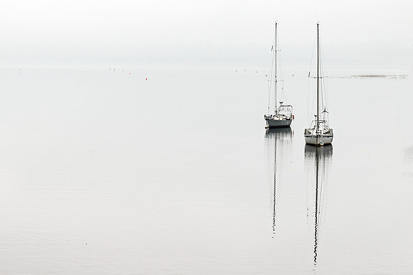 Batiscan: Two small boats sit isolated on a foggy horizon in Batiscan, Quebec